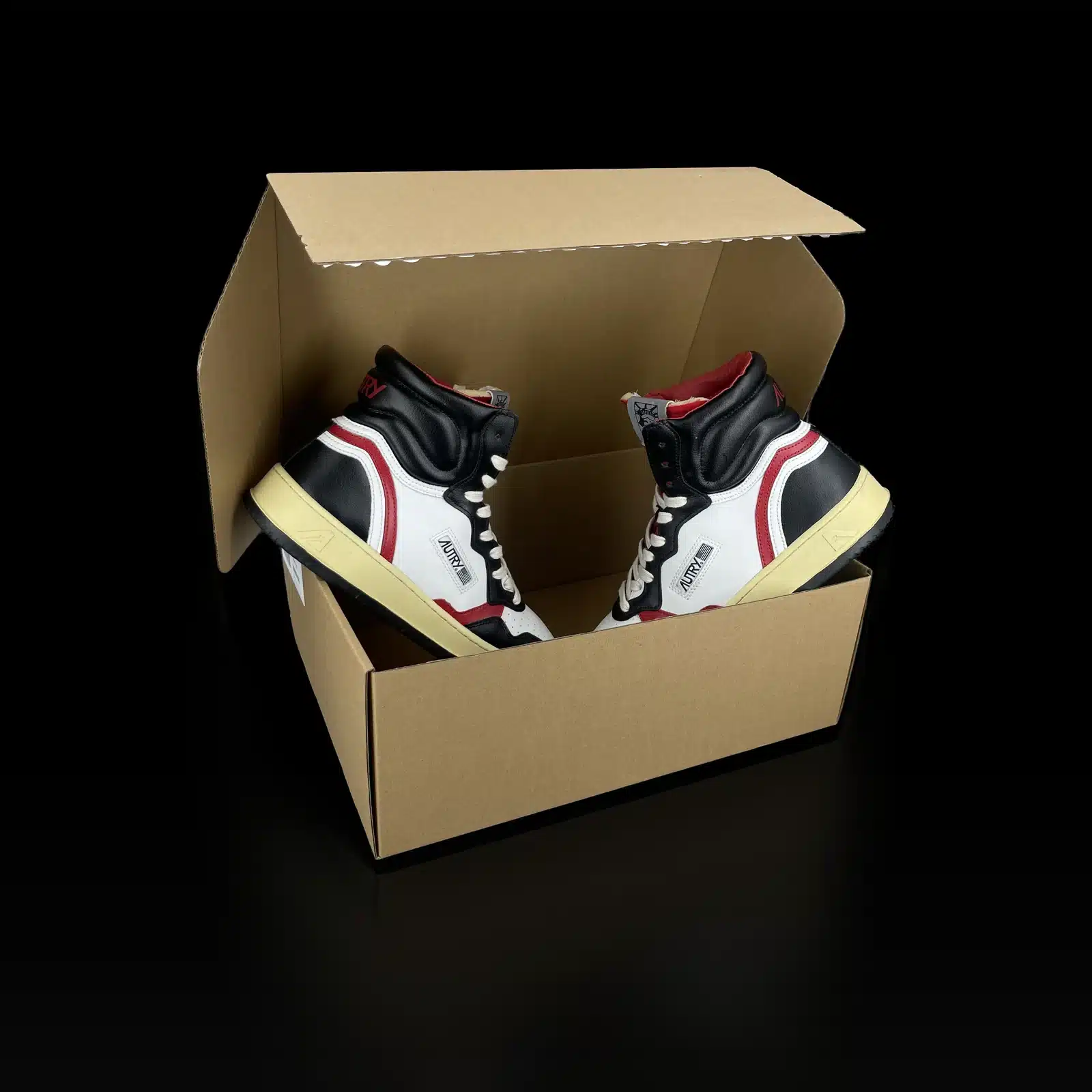 Baskets Autry Medalist Mid blanc, noir et rouge présentées dans une boîte en carton