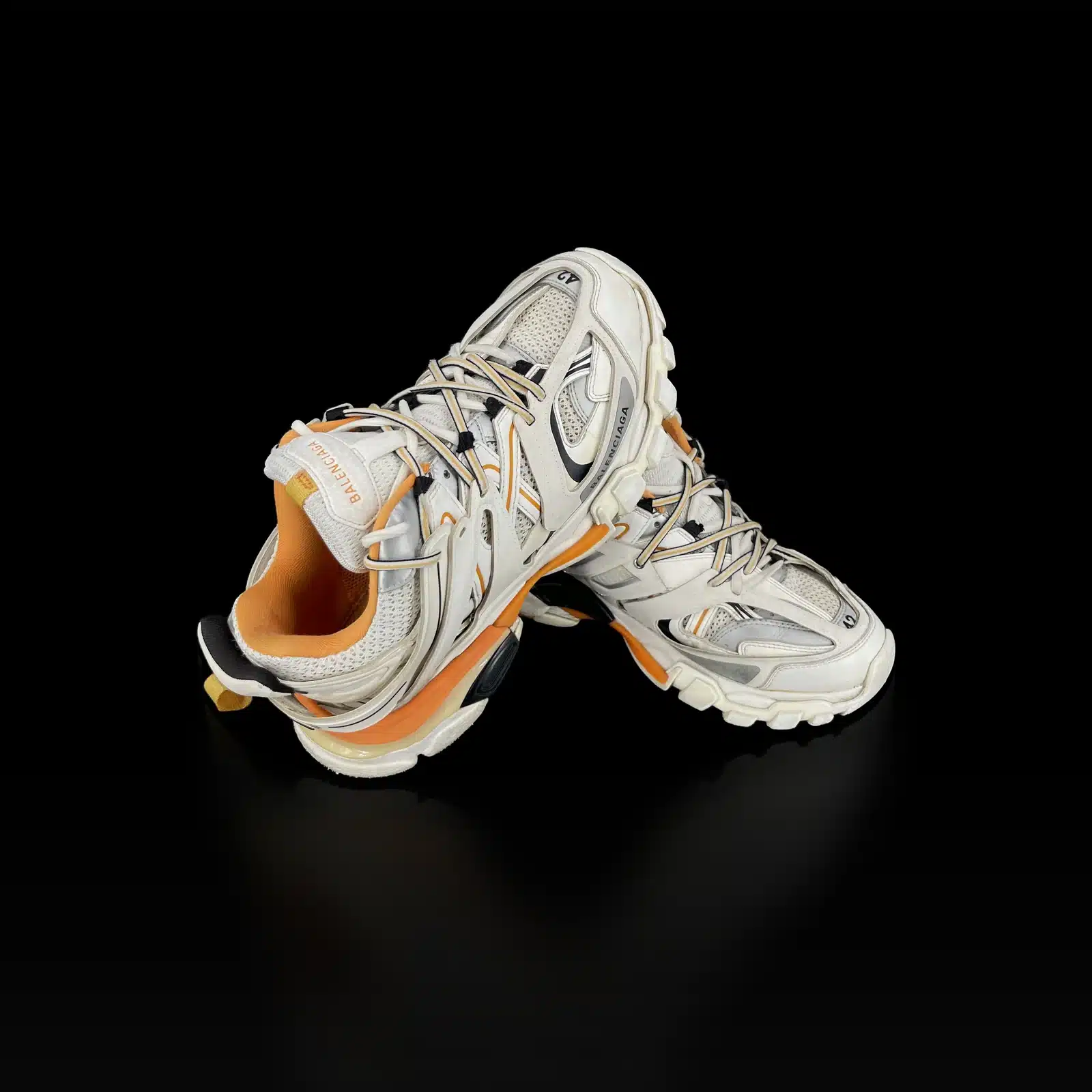 Paire de baskets Balenciaga Track blanc et orange, une chaussure posée sur l'autre