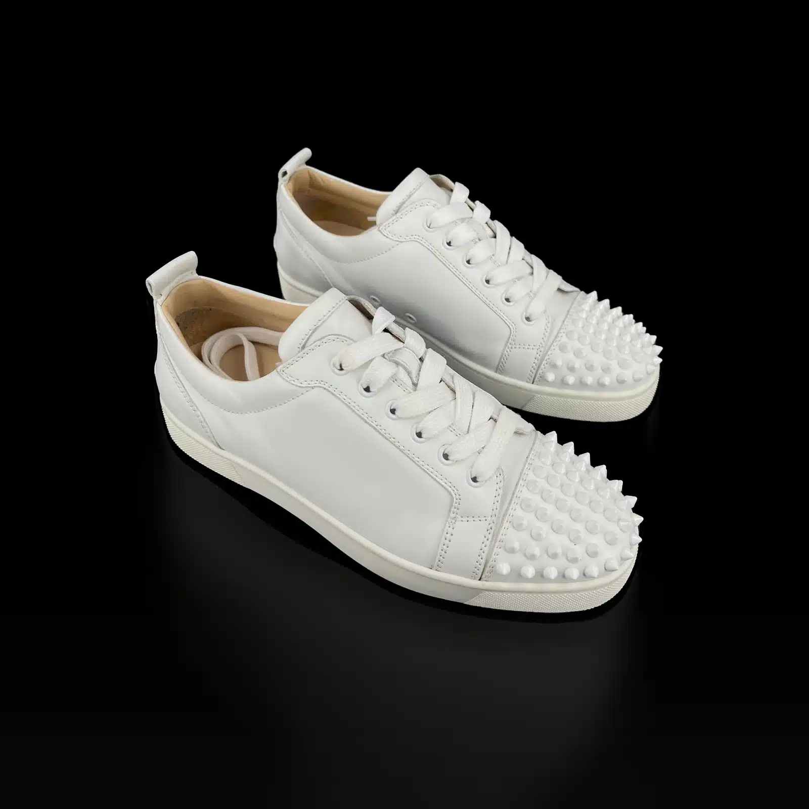 Paire de baskets Christian Louboutin Louis Junior Spikes en cuir blanc à bout clouté, vue de trois quarts
