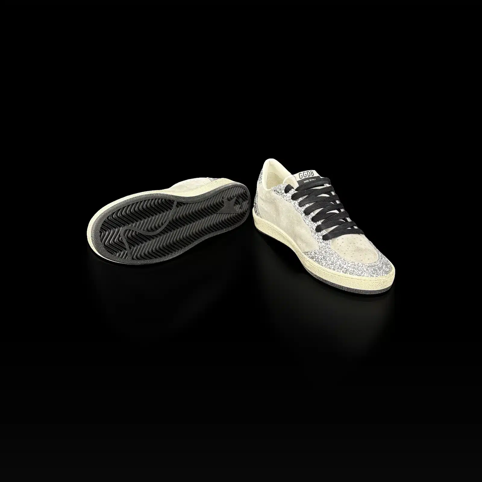 Semelle noire à chevrons et étoile d'une basket Golden Goose Ball Star, à côté de la paire
