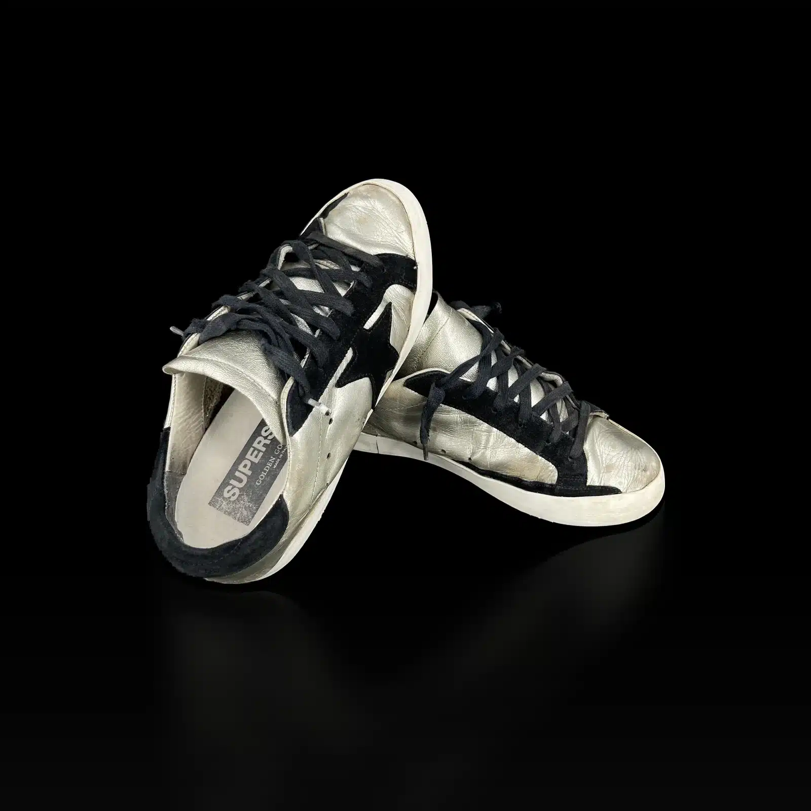 Paire de baskets Golden Goose Super-Star argentées, vue côté talon en daim noir