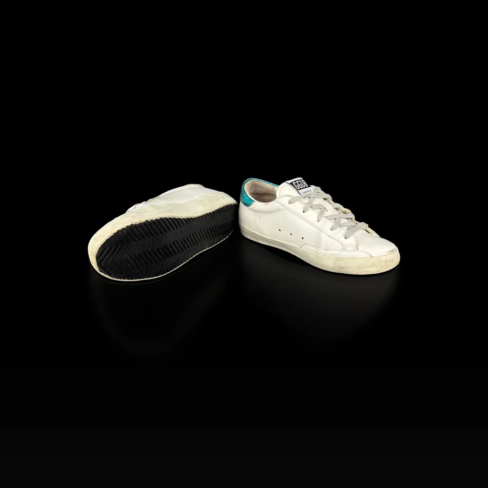 Basket Golden Goose Super Star retournée montrant la semelle noire à chevrons, et basket de profil intérieur