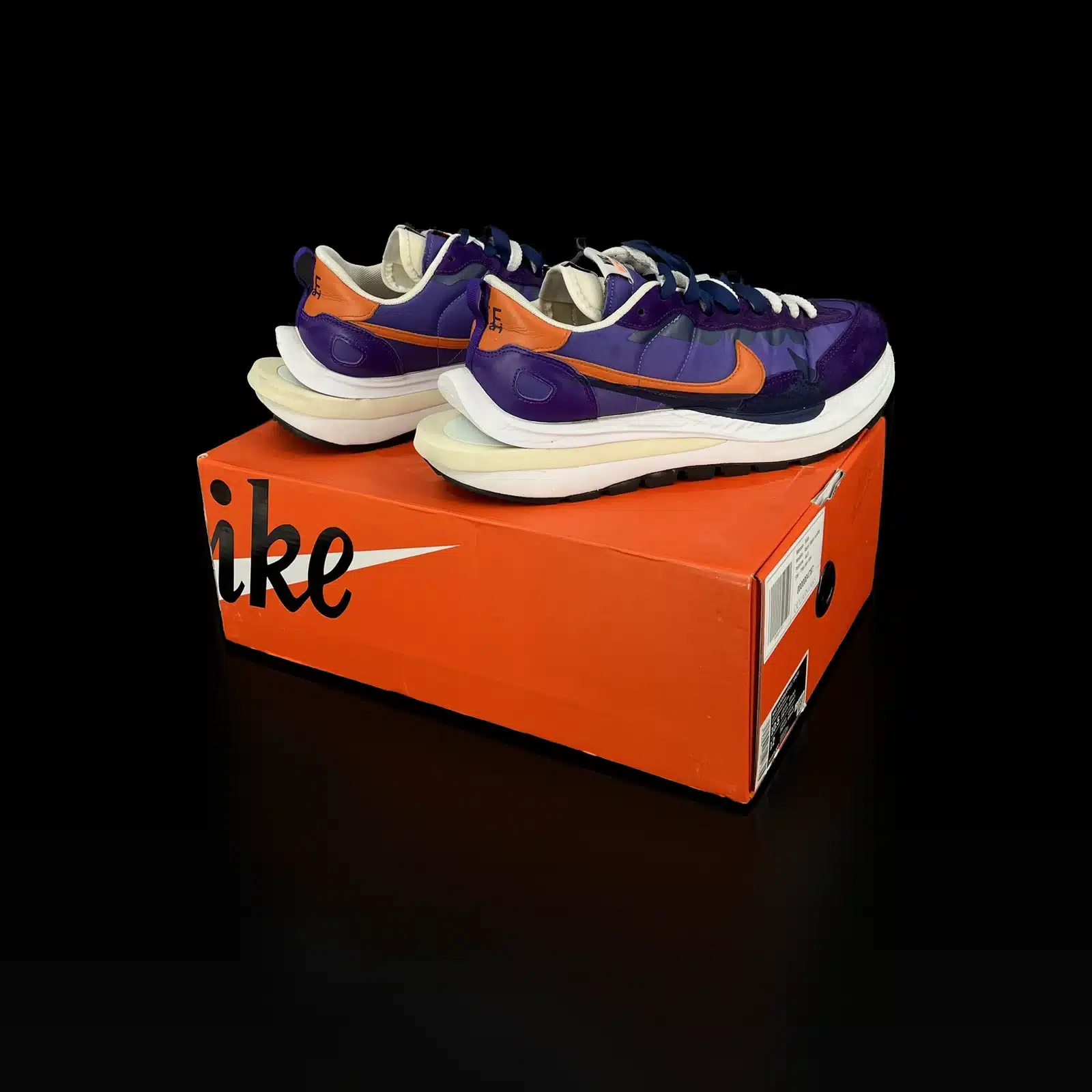 Baskets Nike x Sacai VaporWaffle Dark Iris posées sur leur boîte Nike orange
