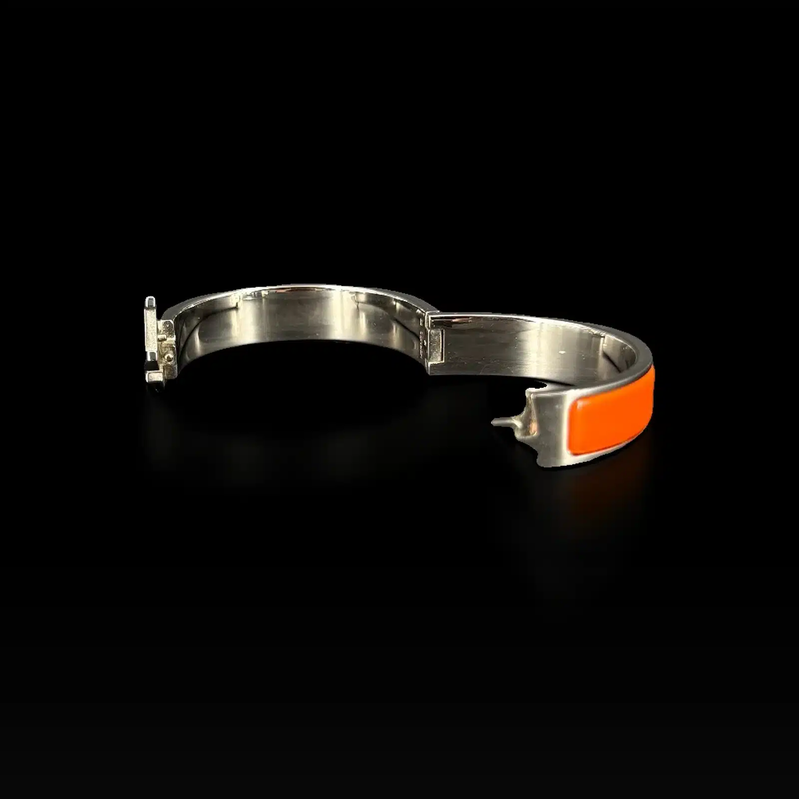 Bracelet Hermès Clic H orange ouvert, charnière et fermoir sur fond noir