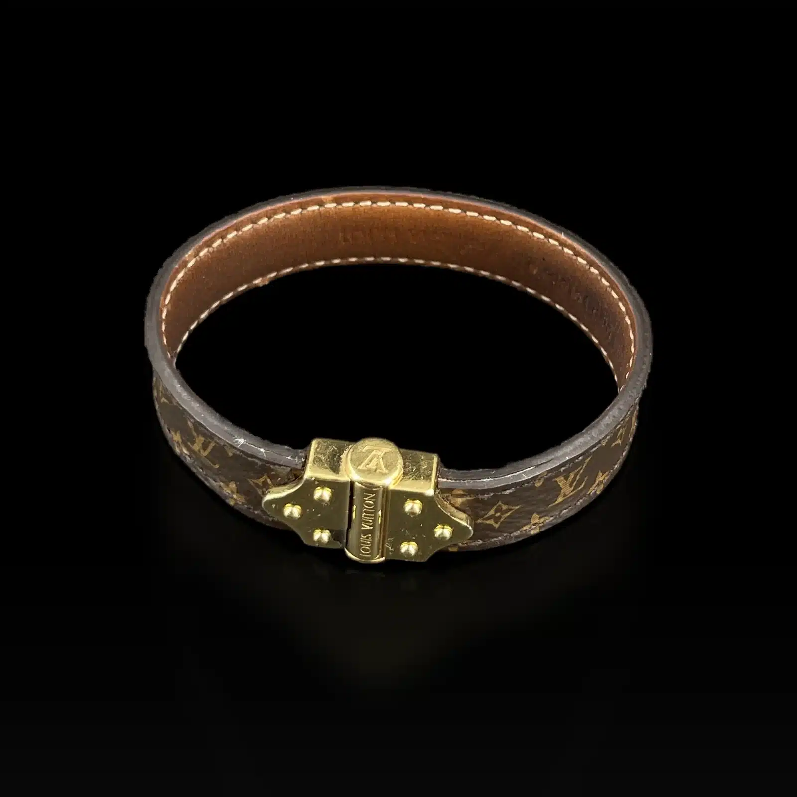 Bracelet Louis Vuitton Nano Monogram vu de dessus, intérieur en cuir naturel surpiqué, sur fond noir