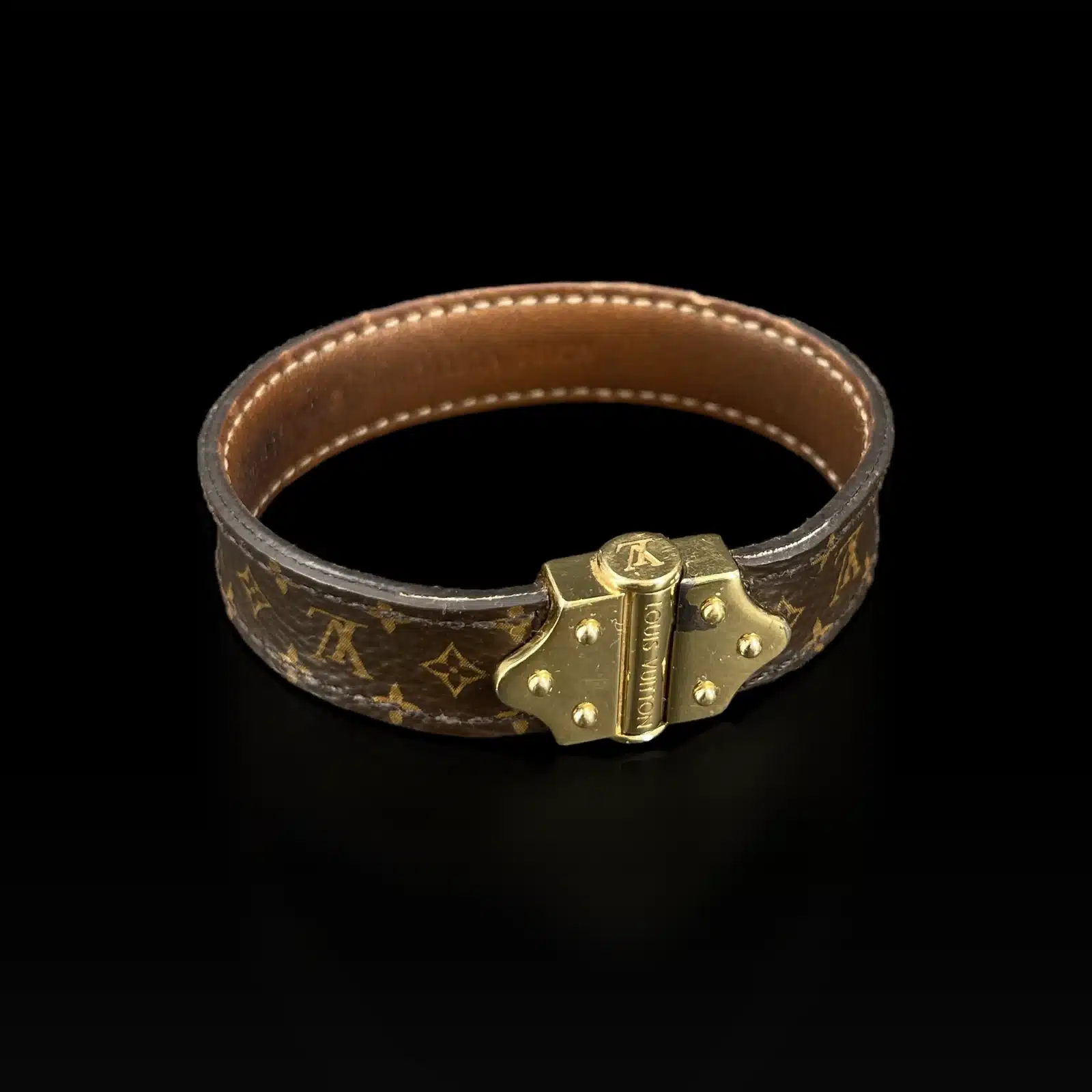 Bracelet Louis Vuitton Nano Monogram, gros plan sur le fermoir doré, sur fond noir