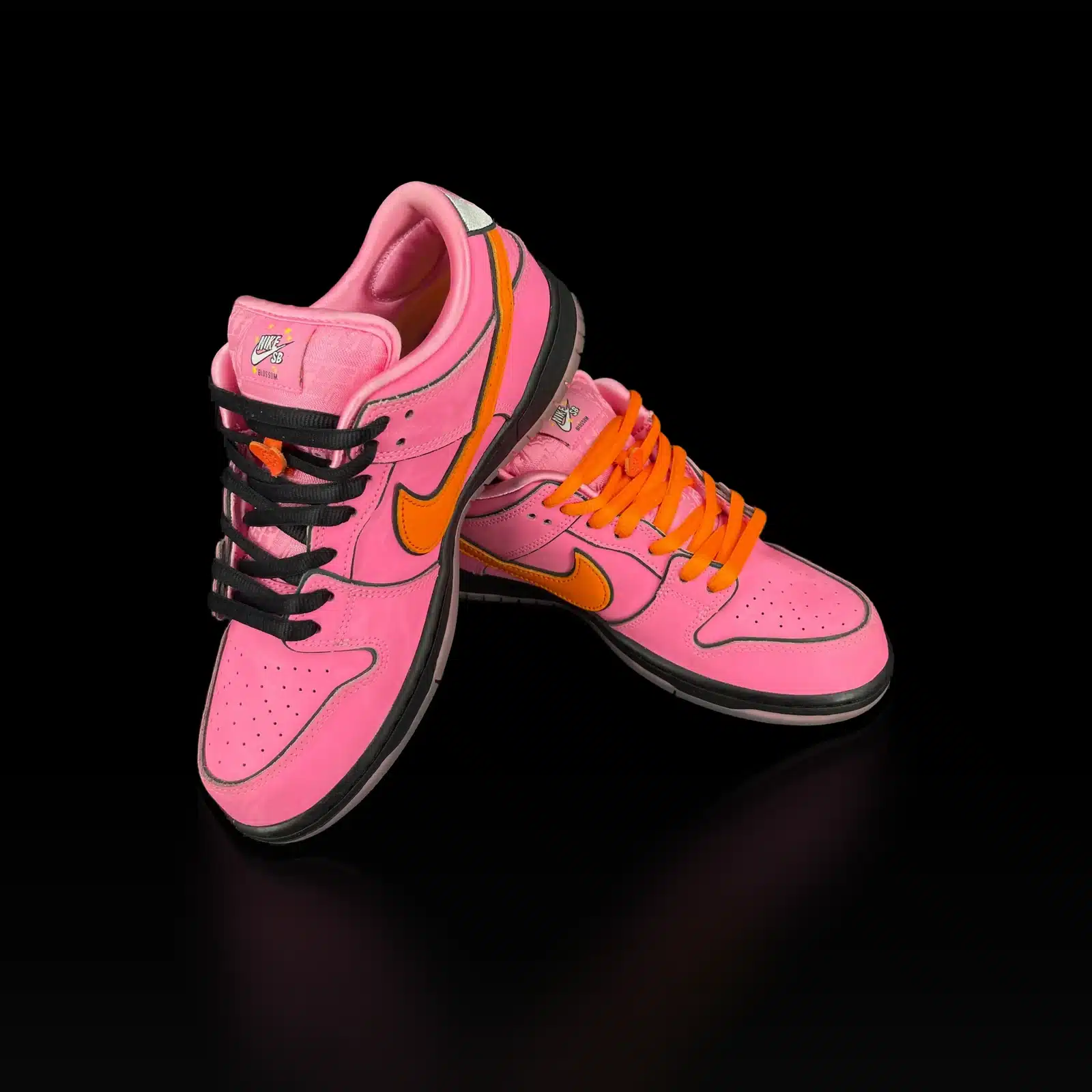 Paire de Nike SB Dunk Low Blossom en nubuck rose avec Swoosh orange, vue de face