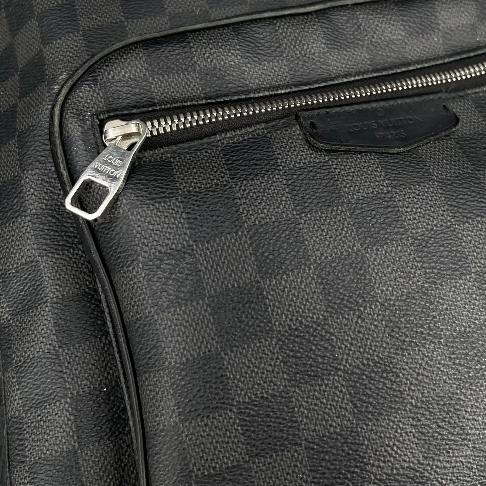 Détail de la poche zippée et de la plaque en cuir du sac à dos Louis Vuitton Josh