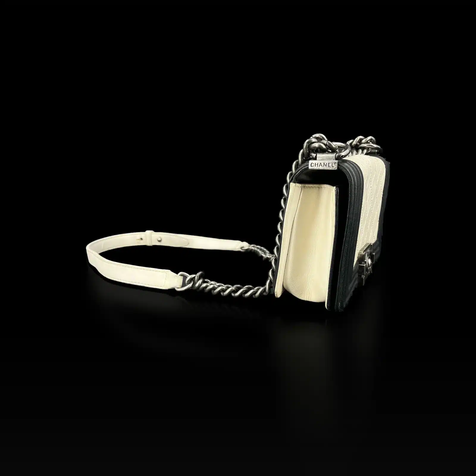 Sac Chanel Boy mini blanc et noir, vue de côté avec bandoulière chaîne et cuir blanc