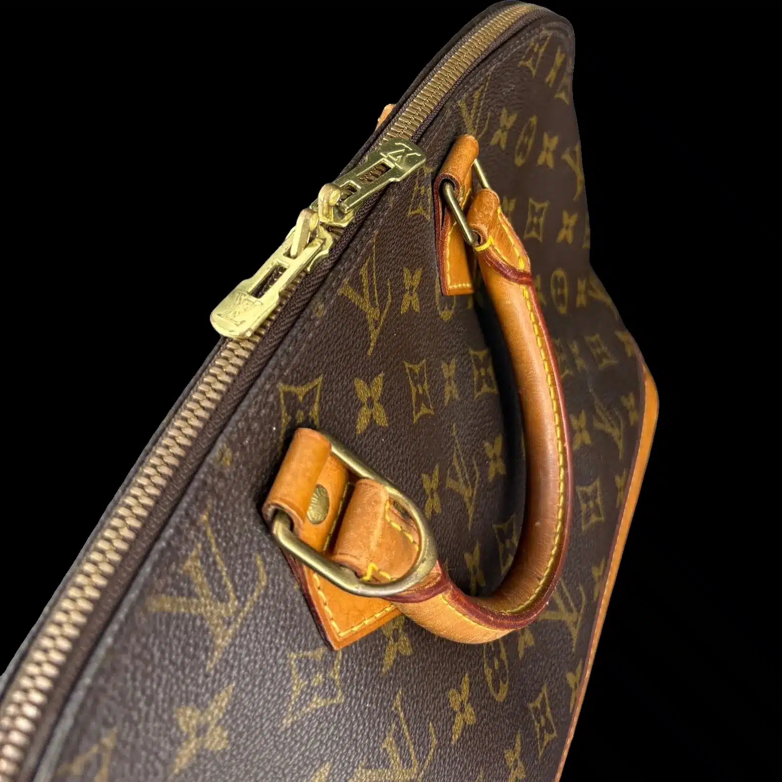 Détail des curseurs dorés LV et de la poignée en cuir patiné du sac Louis Vuitton Alma